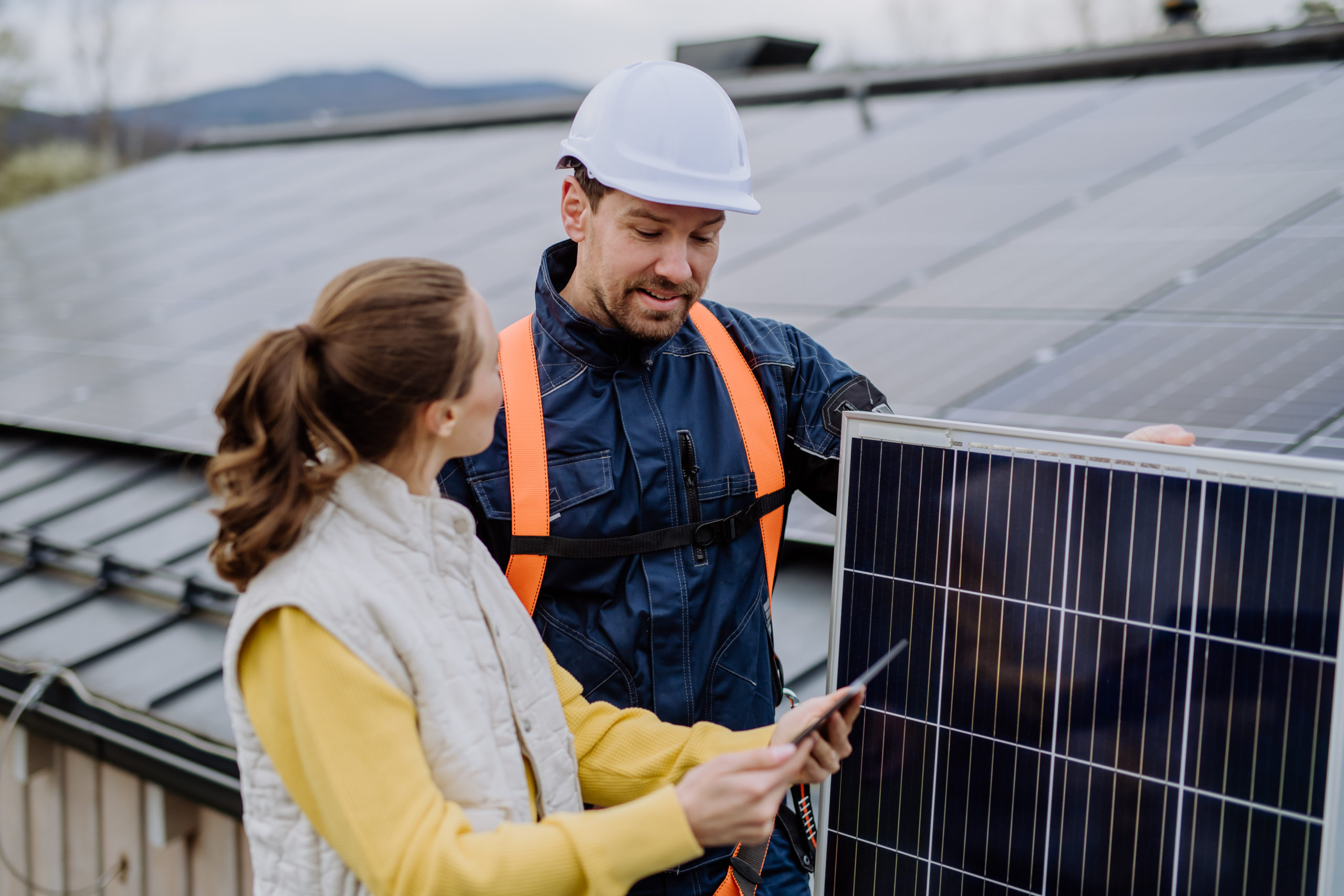 Young Woman Talking With Technician About Solar Panel System.